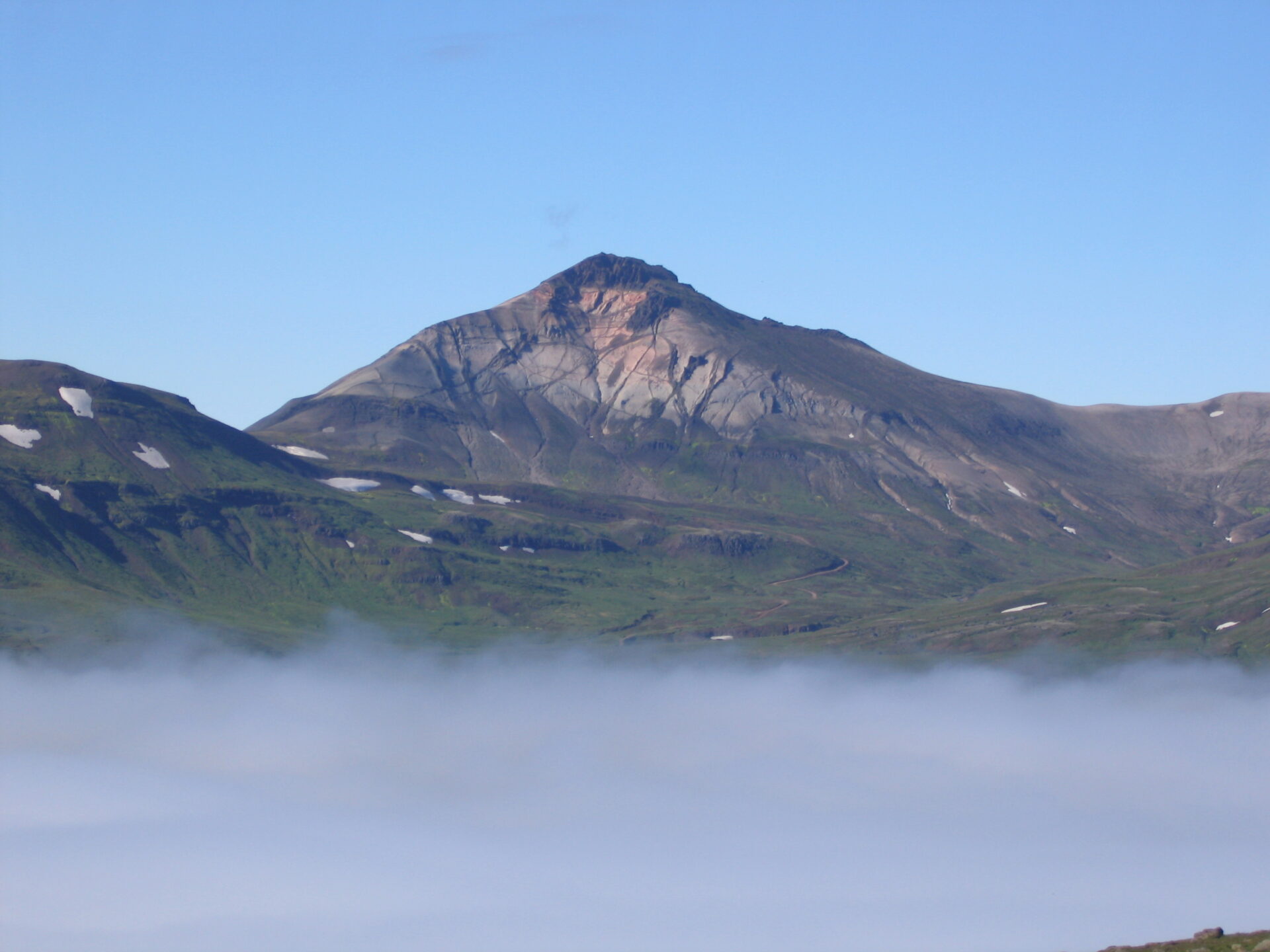 1. mynd. Suðurhlíð Hvítserks alsett basaltgöngum sem skera ljósa flikrubergið þar sem zirkonkristallana er að finna. – South side of Mt. Hvítserkur, NE Iceland, with dark coloured basalt dykes cutting the ignimbrite, which contains zircon crystals. Ljósm./Photo: Olgeir Sigmarsson.